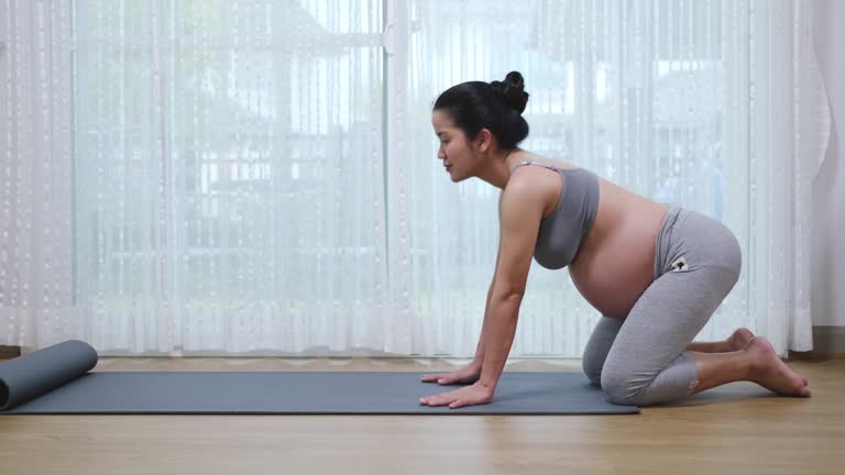 Pregnant Asian mother exercising Yoga in living room