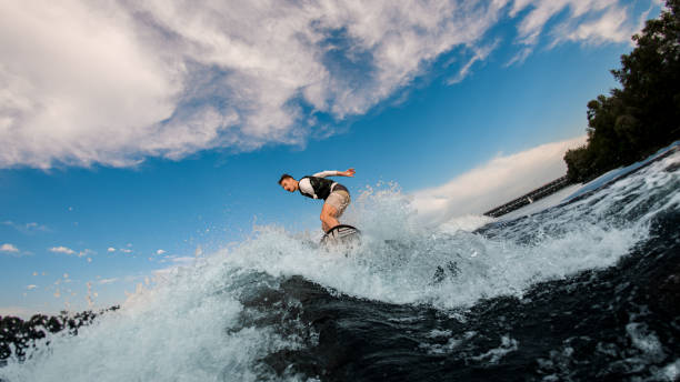 uomo attivo con una mano amputata cavalcare l'onda sul wakeboard - wakeboarding surfing men vacations foto e immagini stock