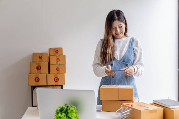 istock A woman using a smartphone to take pictures in front of parcel boxes, parcel boxes for packing goods, delivering goods through private courier companies. Online selling and online shopping concepts. 1338302657