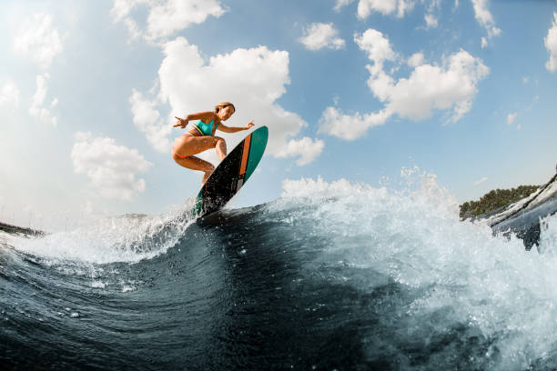 istock Active female wakesurfer skilfully jumping with wakeboard at splashing river wave 1338302740
