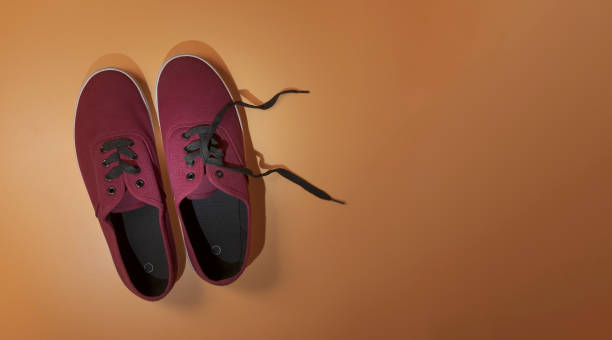 New sneakers. Maroon color. View from above. On mustard background. Copy space