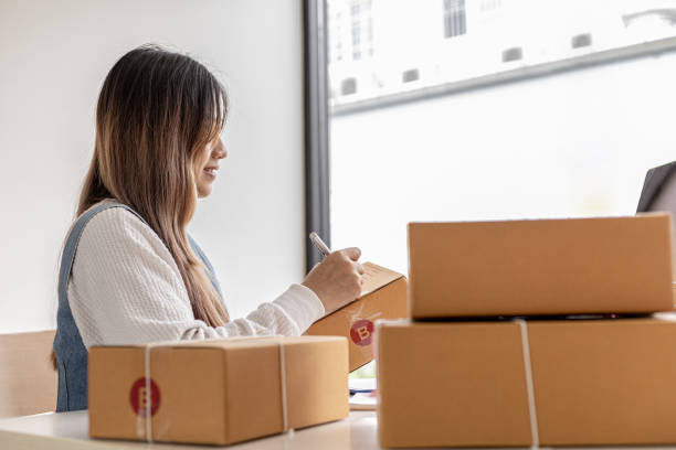 istock Woman holding parcel boxes to write customer address information before shipping to customers via private transport service, she works online, she sells through website. Online selling concept. 1338303802