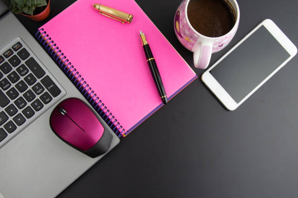 istock computer, pink notebook, fountain pen, phone and a cup of coffee on black background 1338308236