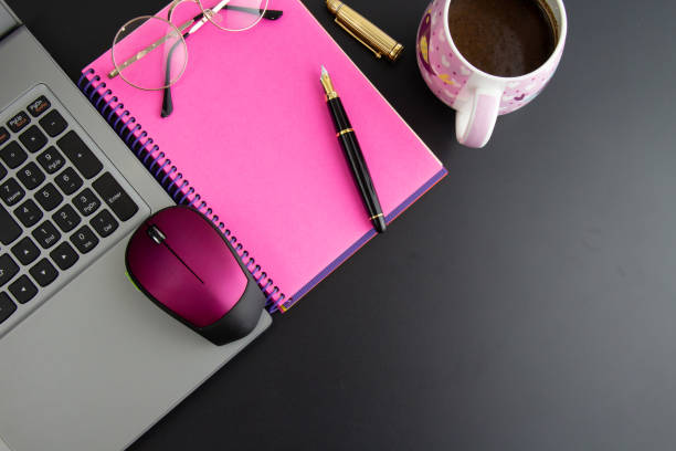 istock computer, pink notebook, fountain pen and a cup of coffee on black background 1338308293