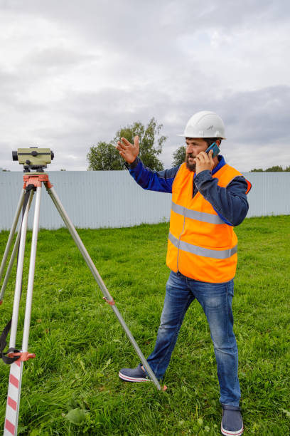 istock A civil engineer with an optical level talking on a mobile phone. 1338309762