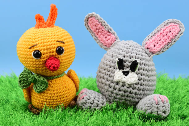 istock Crocheted rabbit and chicken sitting on a green grass carpet 1338310412