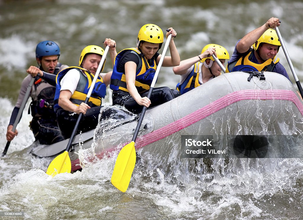 Group of people paddling while whitewater rafting Group of people whitewater rafting on a river Rafting Stock Photo