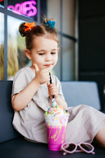 mała dziewczynka pijąca koktajl mleczny przez różowy - cream sprinkles food and drink freshness zdjęcia i obrazy z banku zdjęć