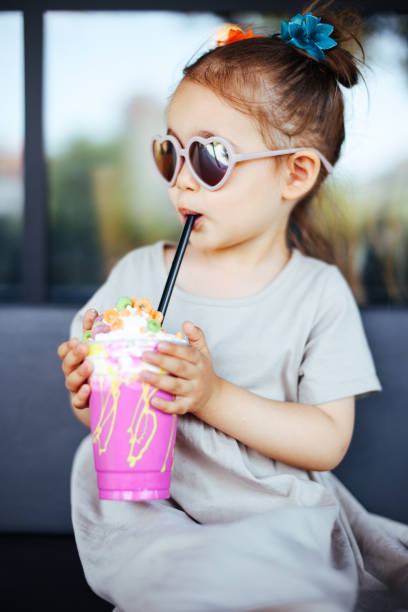 mała dziewczynka pijąca koktajl mleczny przez różowy - cream sprinkles food and drink freshness zdjęcia i obrazy z banku zdjęć