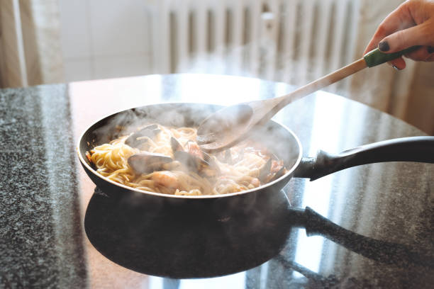 woman cooking mussels pasta spaghetti at home in the kitchen. home cooking or italian cooking concept. - food dinner prepared fish gourmet imagens e fotografias de stock