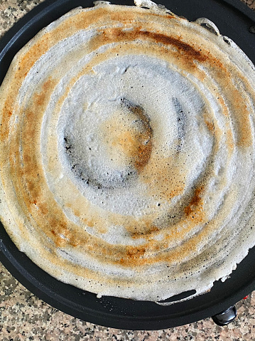 Stock photo showing elevated view of a freshly cooked dosa (India pancake) ready for 
adding a savoury filling of masala potato, onions and coriander.