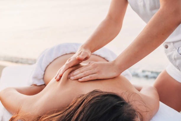 massage spa fille en vêtements blancs sur le bord de mer fait massage du dos à une femme - outdoor chair furniture travel vacations photos et images de collection