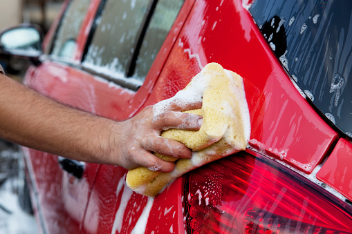 washing a red car with yellow sponge