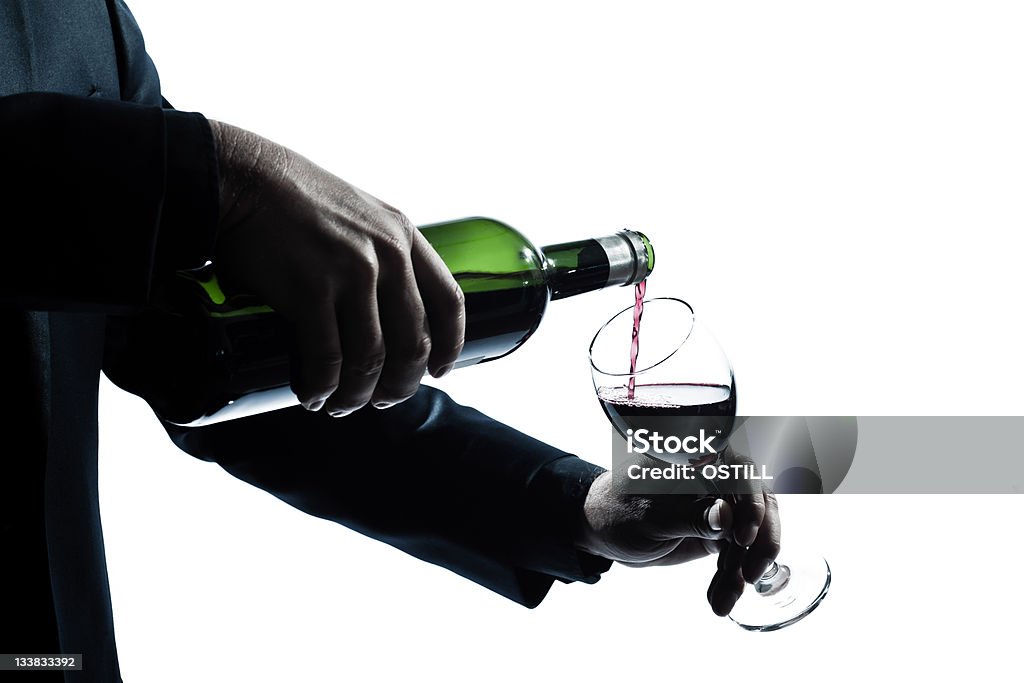 Primo piano di uomo mani versare vino rosso in un bicchiere - Foto stock royalty-free di Vino