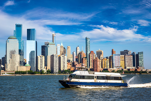 Skyline of Manhattan, New York. Downtown financial district on a clear sky day. Boat passing along the river.