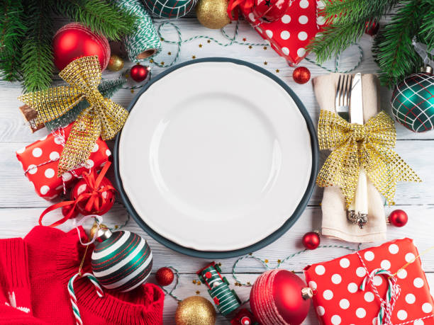istock Christmas festive dinner table setting with decor and cutlery with golden bow, empty white dish 1338344077