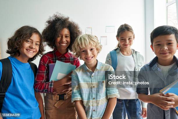 Happy Diverse Junior School Students Children Looking At Camera In Classroom Stock Photo - Download Image Now