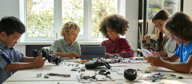 Multiracial school kids students making robotic cars using tablet computer.