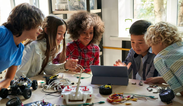 felices estudiantes de escolares diversos que construyen autos robóticos usando computadora. - school children fotografías e imágenes de stock