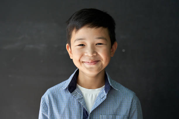 Happy Asian kid boy school student looking at camera at blackboard background. Happy cute Asian kid boy school student looking at camera at blackboard background. Smiling ethnic child pupil posing in classroom. Junior elementary education. Back to school in Asia concept Portrait 8 9 years stock pictures, royalty-free photos & images