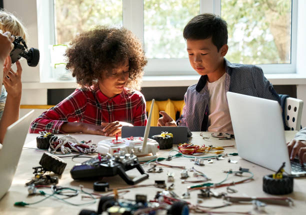 istock Asian school kid boy helping African girl using tablet programming robotic cars. 1338344351