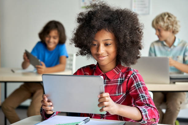 istock Happy African school girl using digital tablet computer at class in classroom. 1338344354