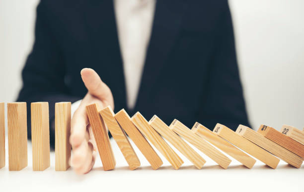 istock Close up businessman hand stop dominoes continuous toppled 1338354121