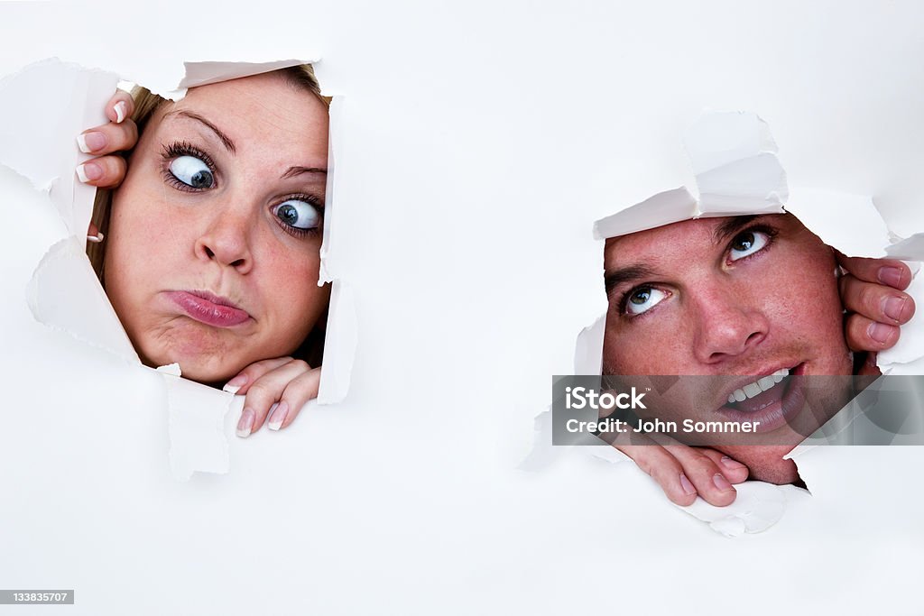 Uomo e donna guardando attraverso fori nella carta - Foto stock royalty-free di Carta