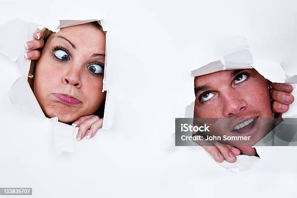 Uomo E Donna Guardando Attraverso Fori Nella Carta - Fotografie stock e altre immagini di Carta - Carta, Foro, Lacerato