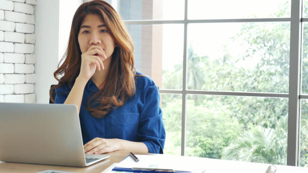Happiness Asian Woman working from home using laptop online meeting in home office. Happy relax time asian business woman typing keyboard use notebook laptop Smiling, laughing at home office. stock photo