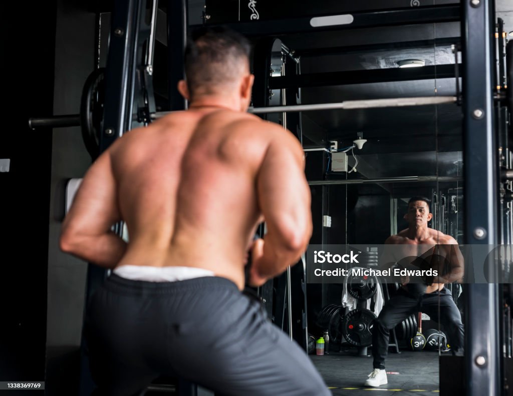 A buff asian male working out at the gym, doing goblet squats. leg and core training workout Squatting Position Stock Photo
