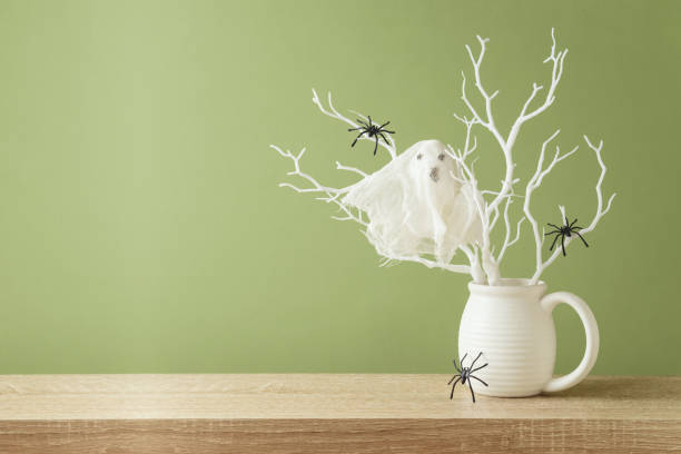 istock Halloween holiday decorations with ghost and branches on wooden table over green background 1338373021