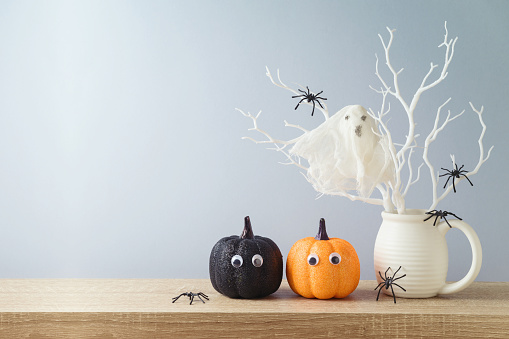 Halloween holiday decorations with glitter pumpkin, spiders and ghost on wooden table.