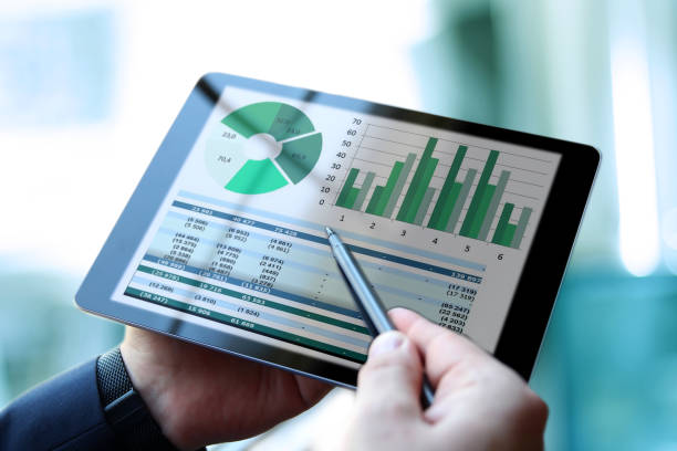 Business man working and analyzing financial figures on a graphs using a tablet stock photo