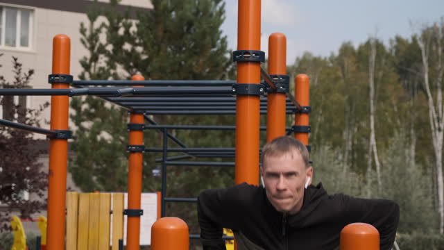 Fit Man Working Out on Parallel Bars Outdoors