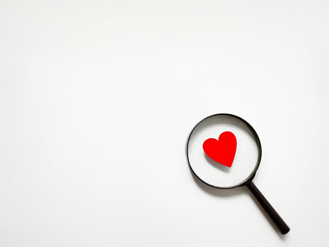 Red heart shaped with magnifying glass background. Stock photo.
