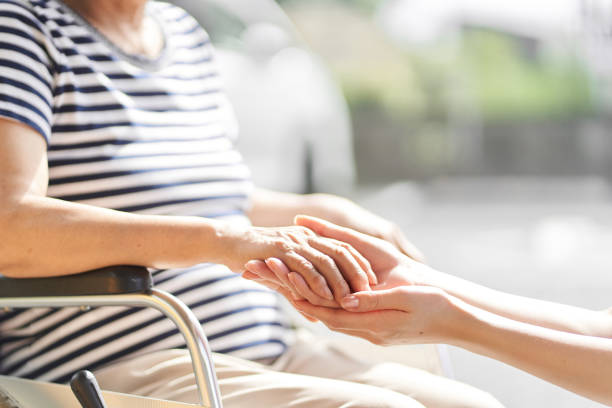 hands of caregivers and elderly people in wheelchairs - ouderenzorg stockfoto's en -beelden