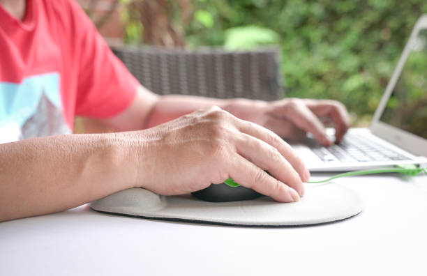 man's fingers clicking on mouse, resting his wrist on wrist rest. - mouse pad imagens e fotografias de stock