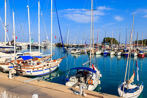 Recreational and fishing boats moored in turquoise waters with residential buildings on cliffs in background.