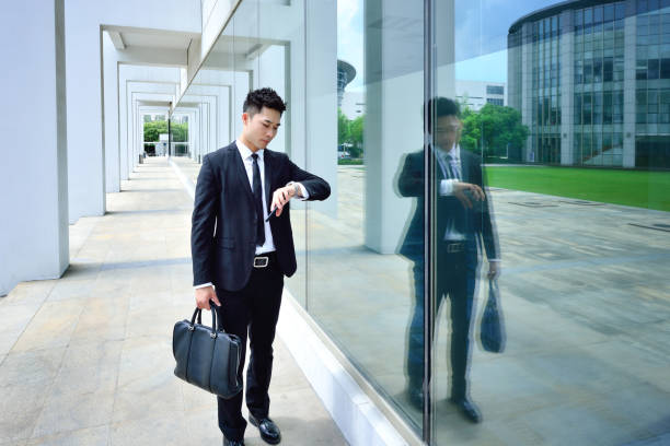 istock One Asian Men Looking at Watch and Standing in Bright Aisle 1338383379