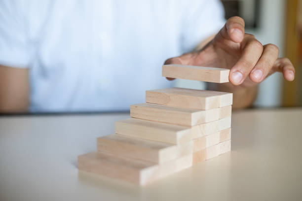 istock Hand arranging wood block stacking as step stair. 1338391320