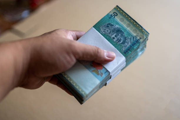 mani maschili che tengono le pile di banconote ringgit rm50 della valuta malese - malaysian ringgit foto e immagini stock
