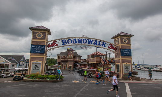 Pedestrians walk by the main entrance of Put-In-Bay's Boardwalk complex on a cloudy summer day