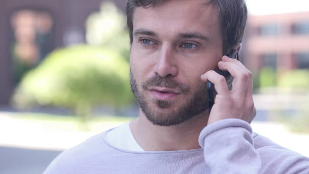 istock Young Man Talking on Phone, Negotiating in Good Mood 1338396117
