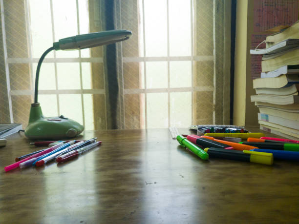 Study table near window with books, Stationary items and a table lamp stock photo