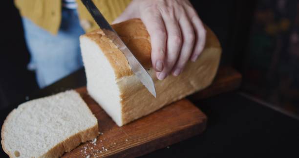 istock Mature woman is cutting bread for breakfast 1338407261