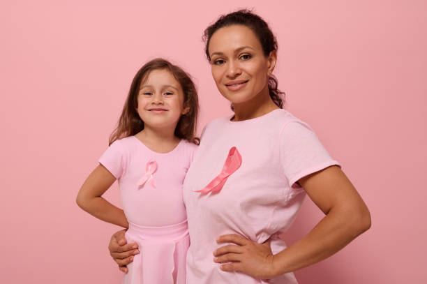 Gorgeous women of two generations, African American lady and European baby girl, in pink clothes and a ribbon, support cancer survivors. Medical Concept October 1. World Breast Cancer Awareness Day