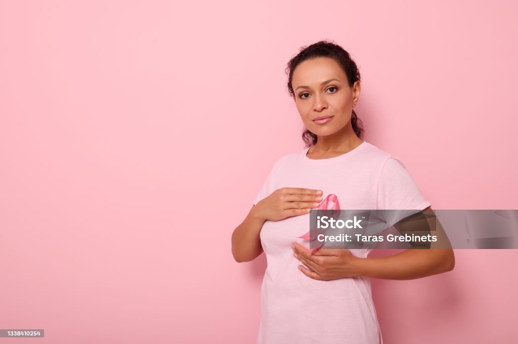 African American woman puts hands around pink ribbon on her pink T Shirt, for breast cancer campaign, supporting Breast Cancer Awareness. Concept of 1 st October Pink Month and women's health care Mixed race woman puts hands around pink ribbon on her pink T Shirt, for breast cancer campaign, supporting Breast Cancer Awareness. Concept of 1 st October Pink Month and women's health care Women Stock Photo African American woman puts hands around pink ribbon on her pink T Shirt, for breast cancer campaign, supporting Breast Cancer Awareness. Concept of 1 st October Pink Month and women's health care Mixed race woman puts hands around pink ribbon on her pink T Shirt, for breast cancer campaign, supporting Breast Cancer Awareness. Concept of 1 st October Pink Month and women's health care Women Stock Photo