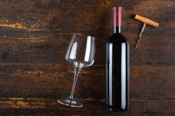 istock Red wine bottle with empty glass and corkscrew on a wooden background. Alcoholic drink. 1338414157