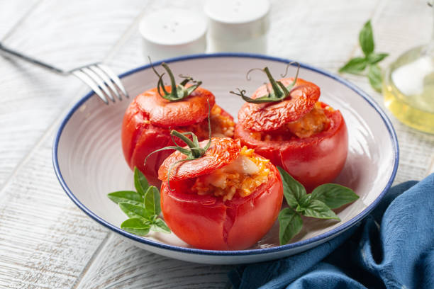 tomates rellenos al horno con arroz y queso. enfoque selectivo, primer plano. mesa blanca. - stuffed tomato fotografías e imágenes de stock